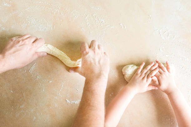 Children's and dad's hands makes raw dough