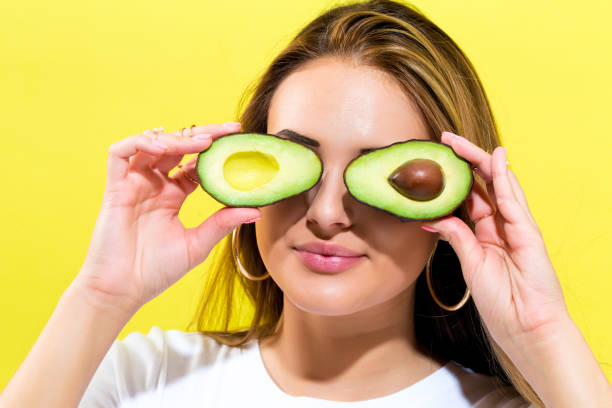 istock Happy young woman holding avocado halves 834772746
