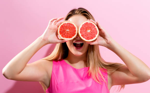 istock Happy young woman holding grapefruit halves 834773044