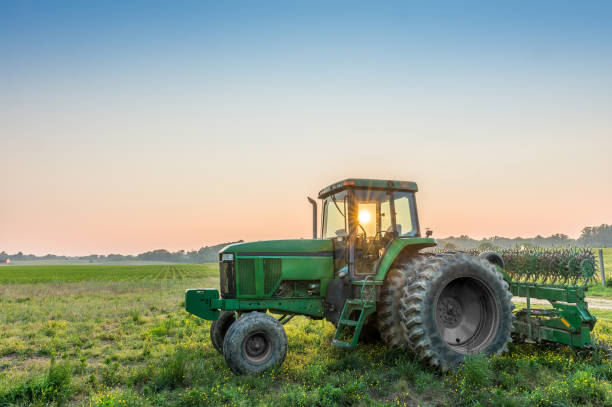 Tractor in a field on a rural Maryland farm Tractor in a field on a rural Maryland farm at sunset with sun rays through tractor cockpit grass area photos stock pictures, royalty-free photos & images
