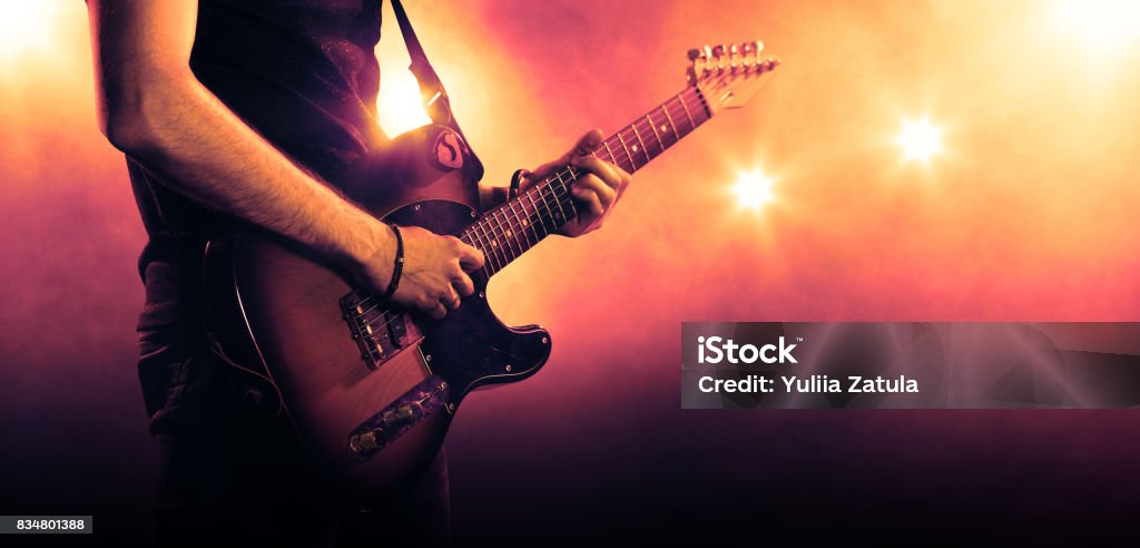 Guitarist playing a guitar, close-up Hand of a musician playing a guitar in backlit Electric Guitar Stock Photo
