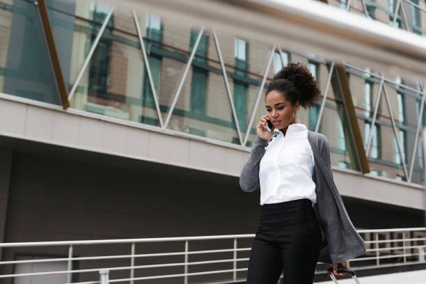 istock Beautiful woman talking on cellphone while walking at building 834821530