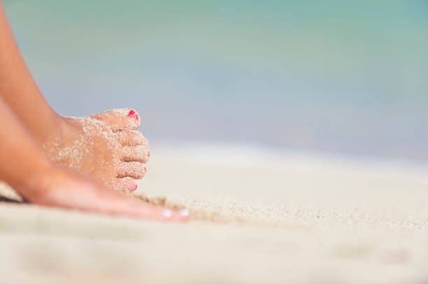 istock Womans hand and foot on a sandy beach. 834829766