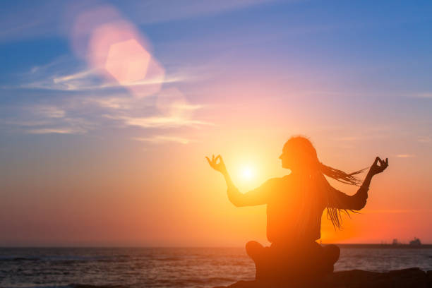 istock Silhouette young woman practicing yoga on the beach at sunset. Meditation. 834831706