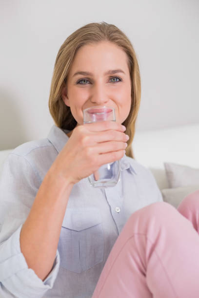 istock Happy casual blonde sitting on couch drinking water 834836612