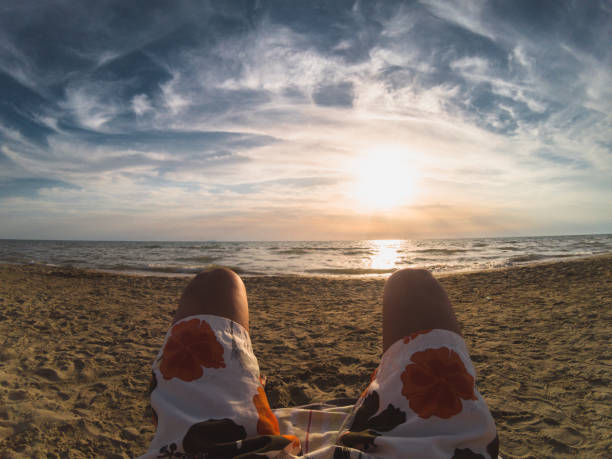 Personal perspective of a young man relaxing at the beach and enjoying a nice sunset