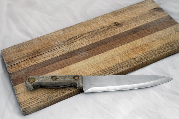 istock Wooden knife on grainy old fashioned cutting board with empty copy space for words. 834853452