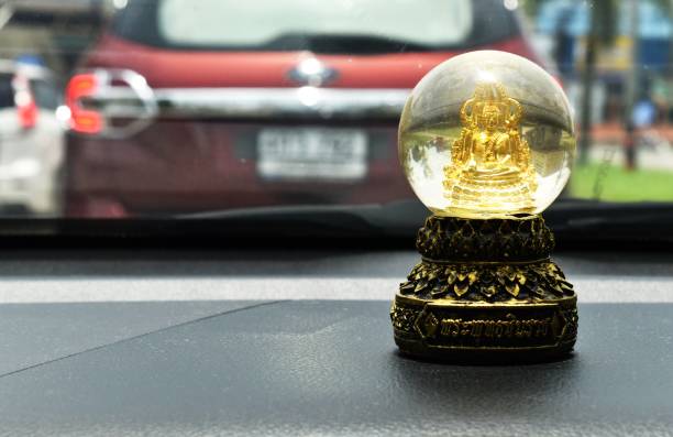 little buddha statue behind windshield in car ,text in thai language is Phraphutthachinnarach