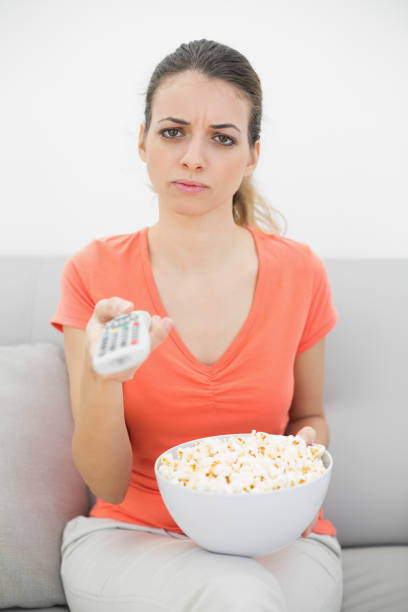 istock Irritated young woman watching television sitting on couch 834984366