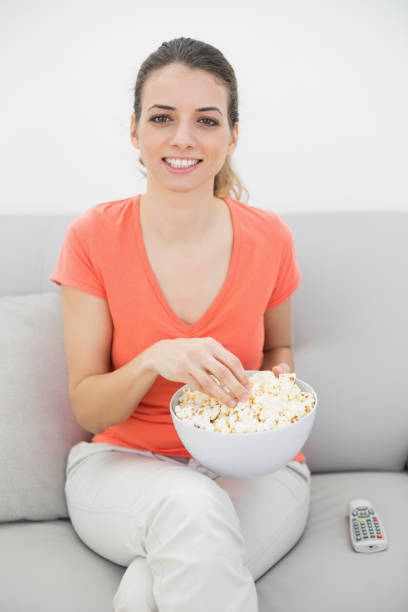 istock Attractive smiling woman eating popcorn while watching television 834984434