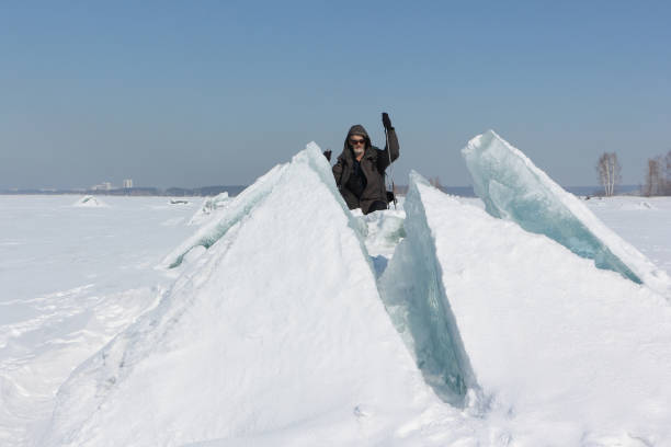 istock Man in sunglasses climbing a cracked ice on a river 834996682