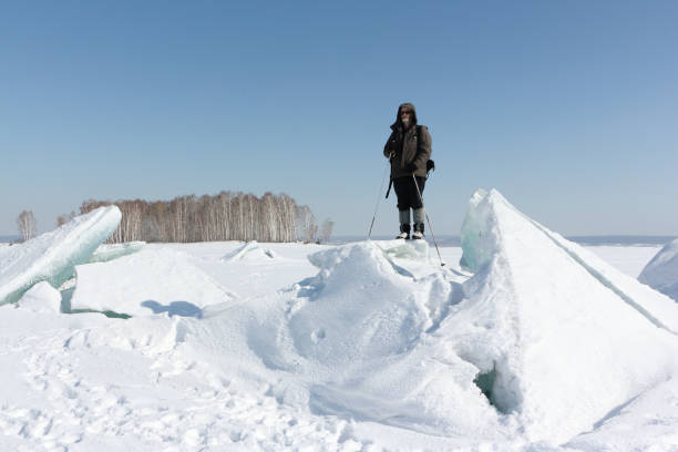 istock Man in sunglasses standing on cracked ice on the river 834996688