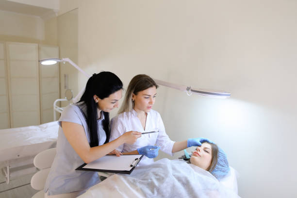 istock Female eyebrow tattoo master teaches girl student to work with c 834997116