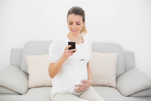 istock Pretty pregnant woman using her smartphone touching her belly 835061892