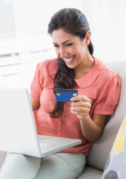 istock Cheerful brunette sitting on her sofa using laptop to shop online 835064854