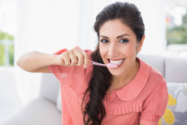 istock Cheerful brunette sitting on her sofa brushing her teeth 835069428