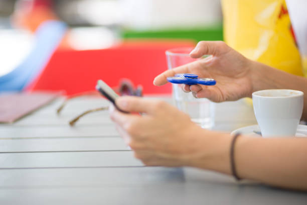 istock Young women is playing with fidget spinner in cafe. 835079104