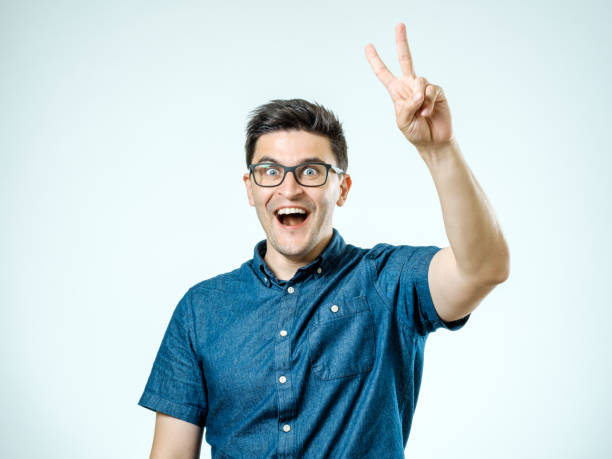 istock Happy man showing victory gesture isolated on gray 835097082