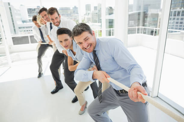 istock Group of business people pulling rope in office 835105780