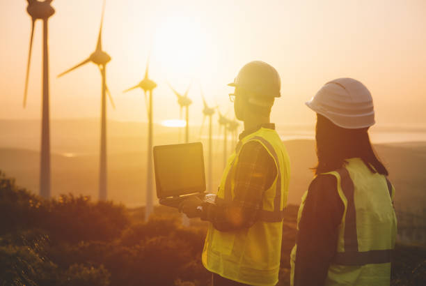 istock Young maintenance engineer team working in wind turbine farm at sunset 835114720