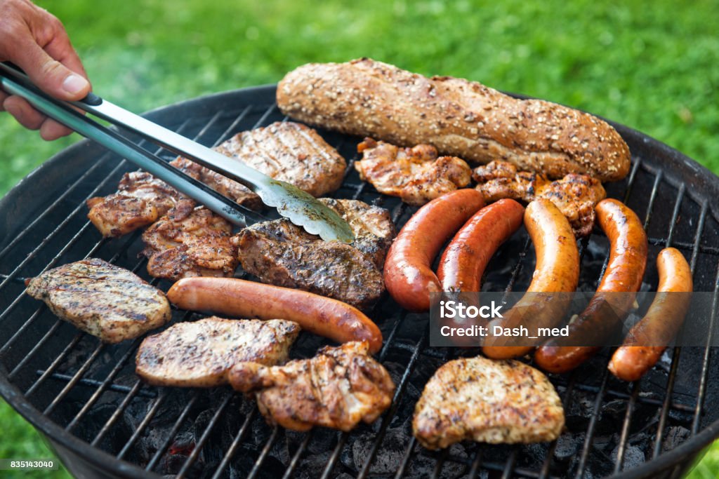 Assorted meat and sausage on grill with the coals, cooking outdoors Assorted meat and sausage on grill with the coals, cooking outdoors, weekend concept Meat Stock Photo