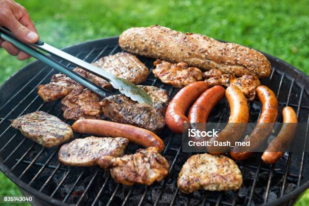 Assorted Meat And Sausage On Grill With The Coals Cooking Outdoors Stock Photo - Download Image Now