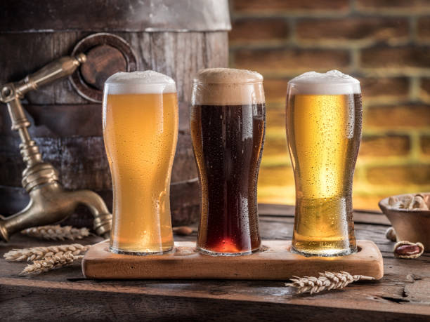 Glasses of beer and ale barrel on the wooden table. Craft brewery. Glasses of beer and ale barrel on the wooden table. Craft brewery. craft beer stock pictures, royalty-free photos & images