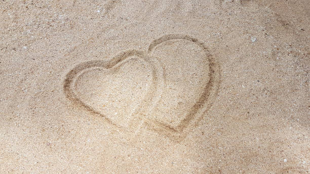 istock man writing the heart on golden sand 835144332