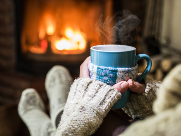 calentamiento y relajación junto a la chimenea con una taza de bebida caliente. - té bebida caliente fotografías e imágenes de stock