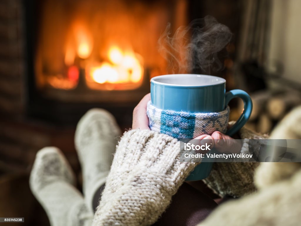 Riscaldamento e relax vicino al camino con una tazza di bevanda calda. - Foto stock royalty-free di Inverno