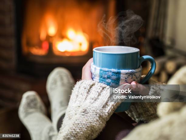 Riscaldamento E Relax Vicino Al Camino Con Una Tazza Di Bevanda Calda - Fotografie stock e altre immagini di Inverno