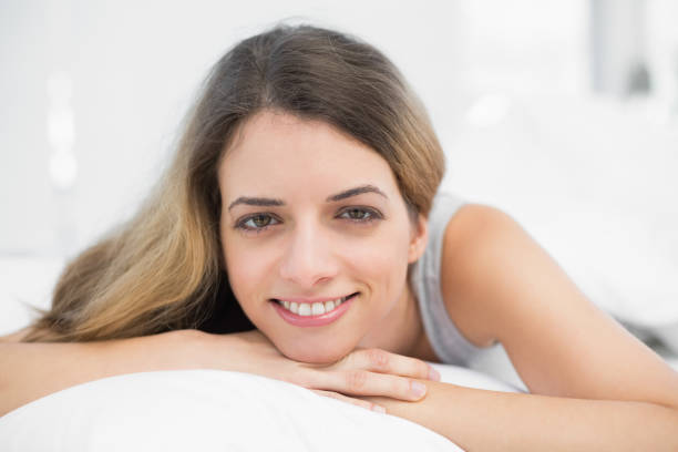istock Beautiful brunette woman smiling at camera lying on her bed 835151078