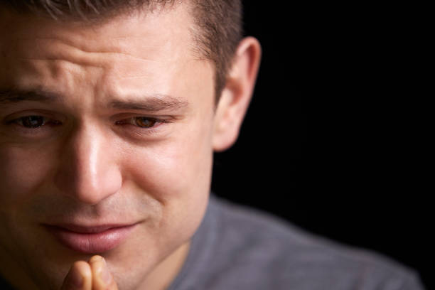 Close up of crying young white man looking down, horizontal