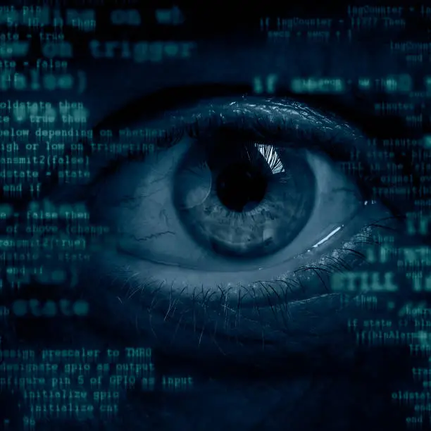 Male eye peeking throuth computer screen. Global surveillance or cybercrime concept.