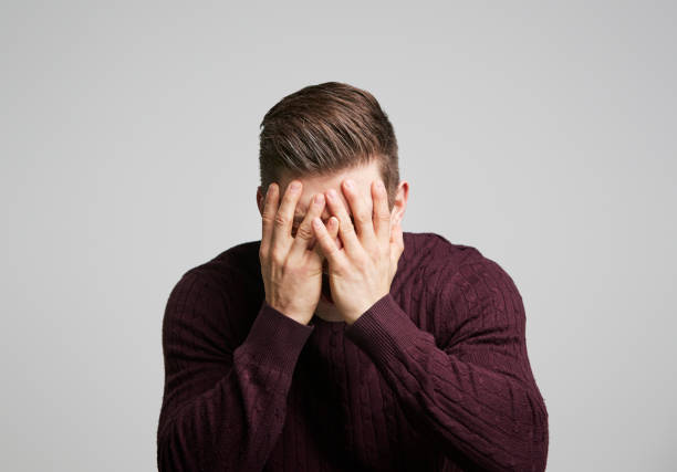 portrait of a young white man with hands covering his face - head in hands imagens e fotografias de stock