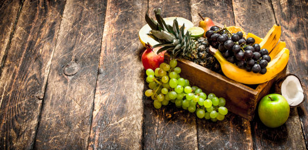 Various ripe fruits in a wooden box. On a wooden table.