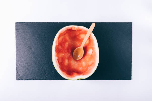 Eaten watermelon on a white table and wooden spoon top view