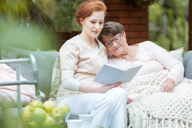 Elder lady resting Elder lady in glasses covered with blanket resting her head on nurse's shoulder hospice photos stock pictures, royalty-free photos & images