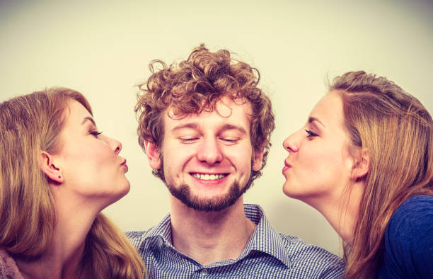 istock Two pretty young women kissing handsome man. 835303782