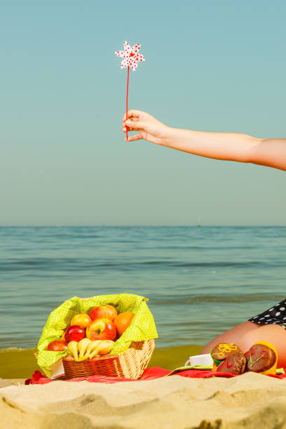 istock Woman hand holding windmill, sea in background 835318294
