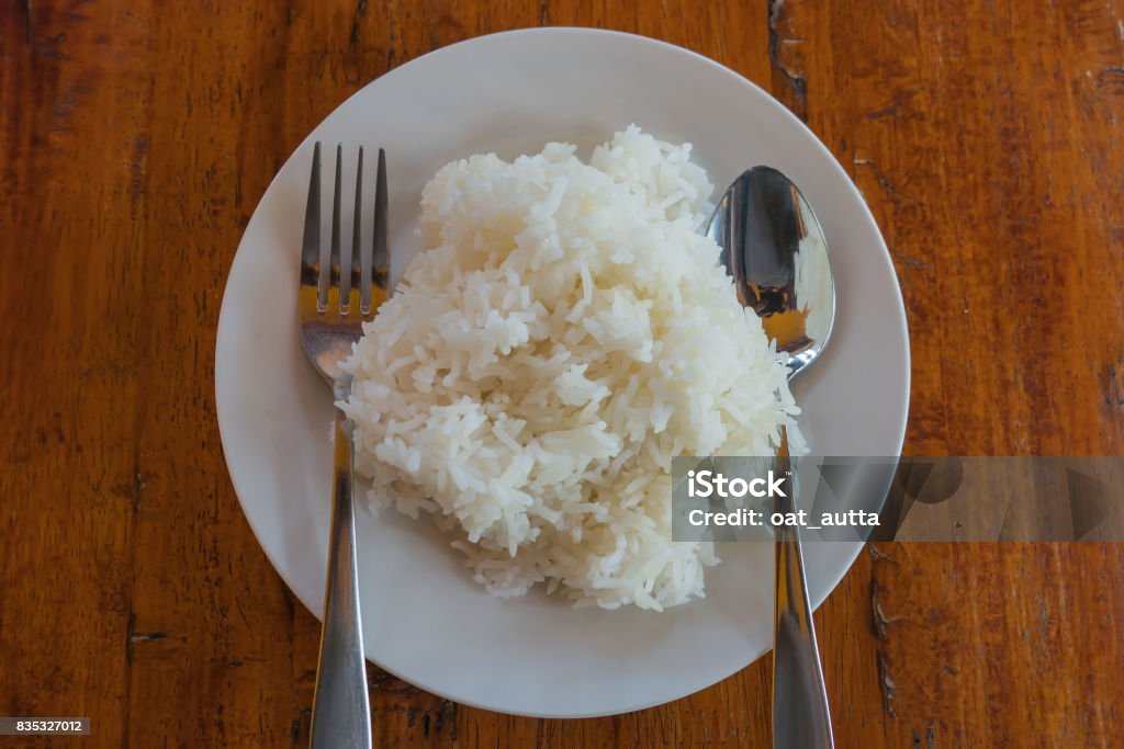 Cooked rice in a Plate and spoon on a table background Cooked rice in a Plate and spoon on a table background. Asia Stock Photo