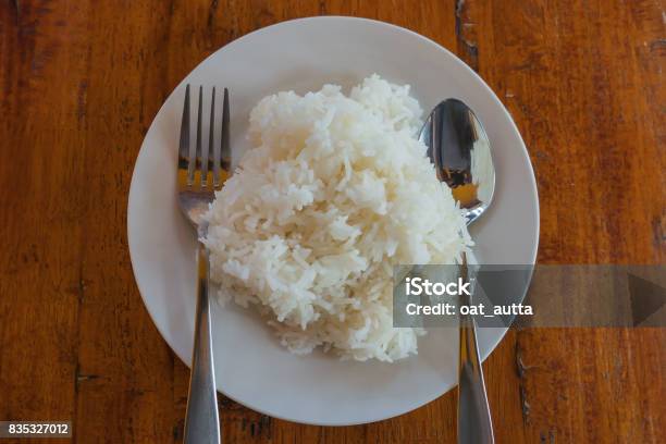 Cooked Rice In A Plate And Spoon On A Table Background Stock Photo - Download Image Now