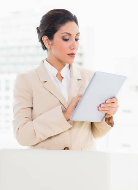 istock Businesswoman standing behind her chair using digital tablet 835334634
