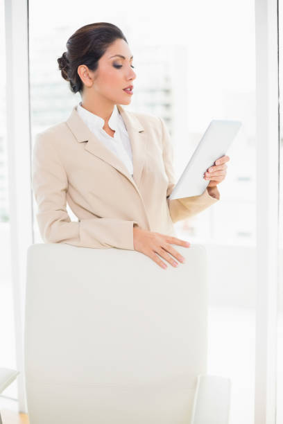 istock Businesswoman standing behind her chair holding tablet pc 835334802