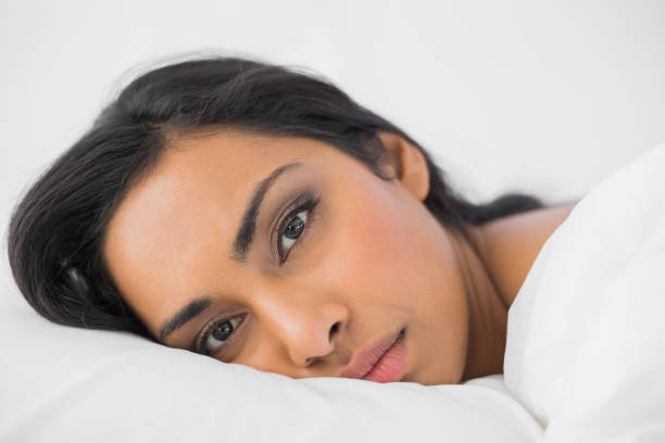 istock Attractive woman lying in her bed looking seriously at camera 835341654