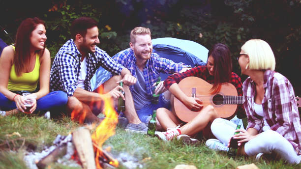 istock Five friends sitting next to campfire and singing song 835350756