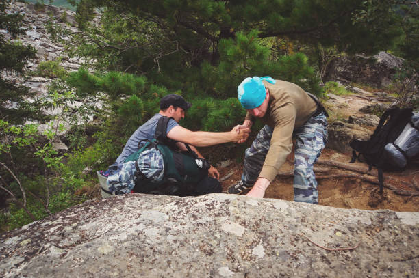 istock Camper helps another to climb the rock. 835383326