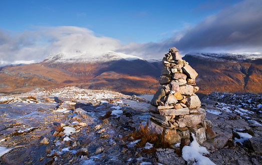 A mountain Cairn on Beinn Eighe with the summits of Slioch and Beinn a Mhuinidh in the distance. Scottish Highlands, Scotland, UK.