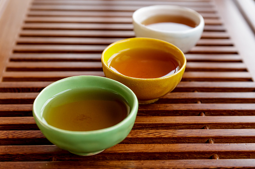 Coloful pialas or teacups with tea on wooden teabord for traditional Chinese tea ceremony, selective focus