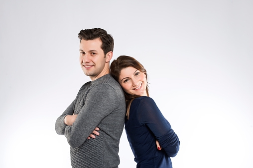 A man and a woman standing back to back on white background